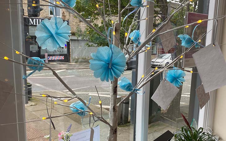 a tree with blue ruffles hung on the end of the branch.